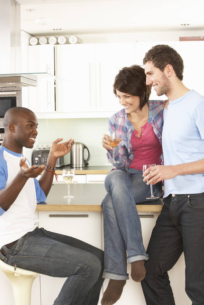 Group Of Young Friends Enjoying Glass Of Wine In Modern Kitchen - Photo, image
