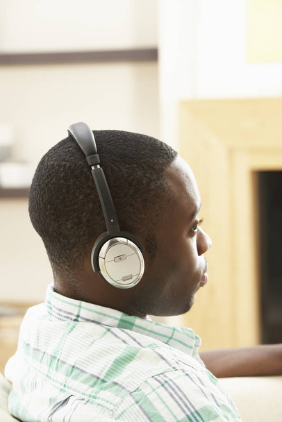 Young Man Relaxing Sitting On Sofa Listening to Music At Home On Headphones - Fotoğraf, Görsel