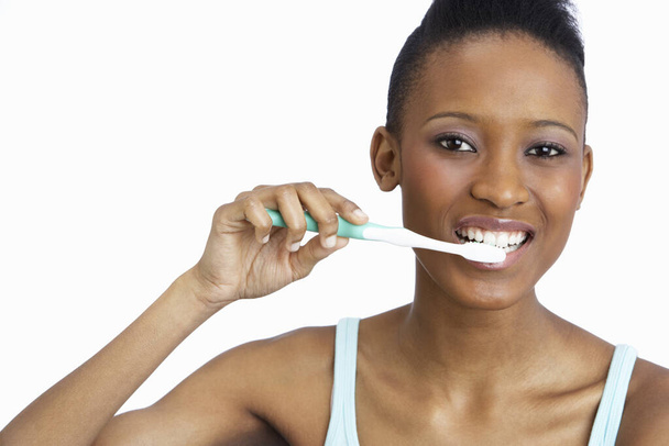 Young Woman Brushing Teeth In Studio - Fotografie, Obrázek