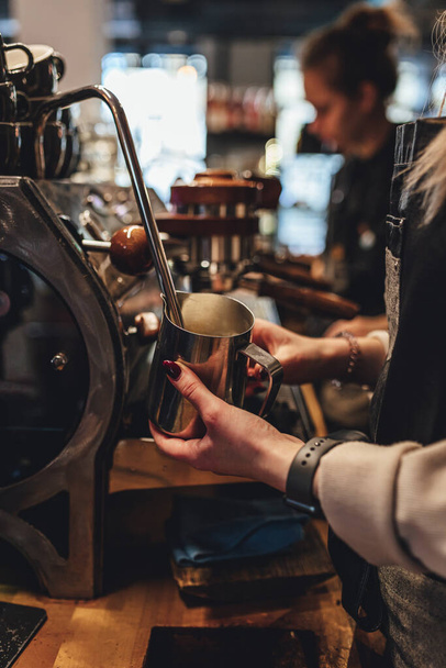 Kahve dükkanında kahve için süt buharı yapan barista. Kahve makinesi. - Fotoğraf, Görsel