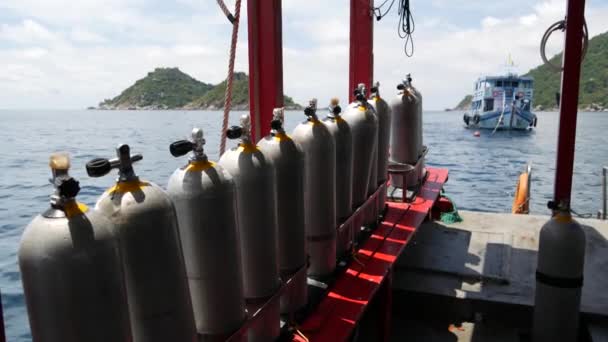 Row of oxygen tanks and diving equipment placed on modern boat in rippling ocean near Koh Tao resort, Thailand. Concept of tourist sports extreme entertainment, adventure and new experience. - Footage, Video