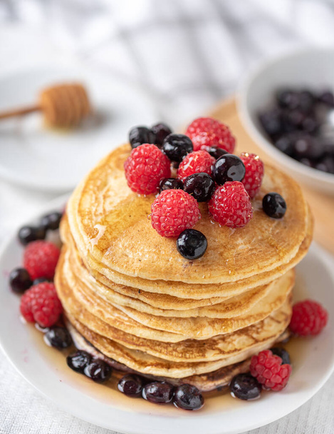 Sweet homemade pancakes with raspberries and blueberries on white plate. - 写真・画像