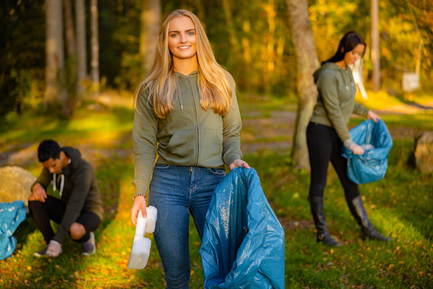 Young female volunteer holding garbage bag at park - Photo, Image