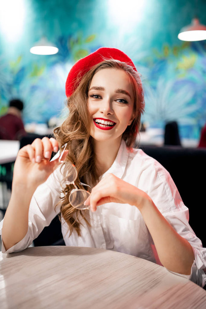 Portrait young happy retro france girl in red beret and white shirt with snow-white smile, breakfast in cafe - Photo, Image