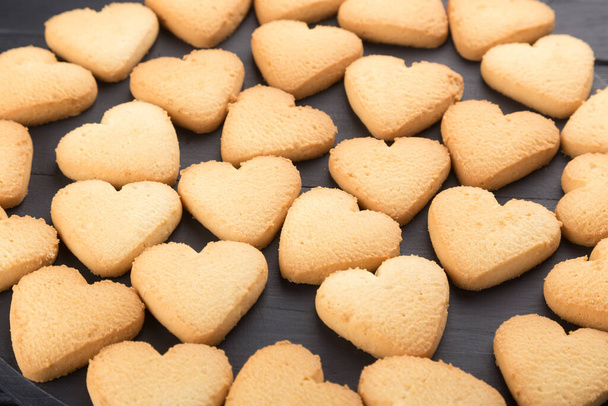 Biscotti a forma di cuore decorati per San Valentino. Spazio libero per il testo. Due biscotti a forma di cuore con marmellata su un tavolo di legno nero. Piatto di legno con biscotti a forma di cuore su un tavolo di legno nero. Come una cartolina. Contesto con i cookie
 - Foto, immagini