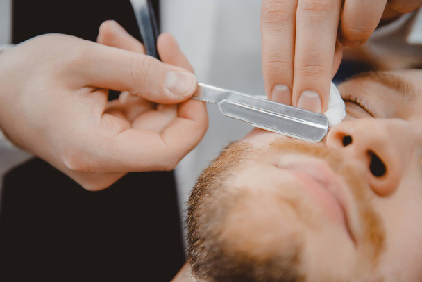 Mann mit Bart Kunde in Friseursalon Friseur rasiert sich mit gefährlichem Rasiermesser - Foto, Bild