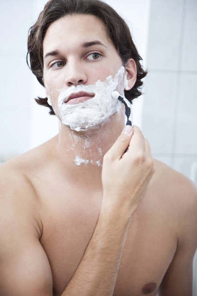 young handsome man with beard shaving face in bathroom - Fotó, kép