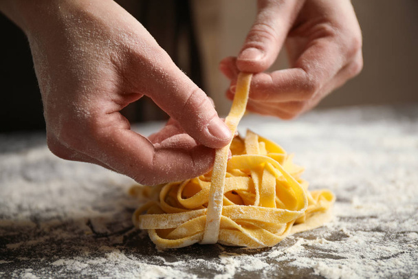 Woman holding pasta at table, closeup view - Foto, afbeelding
