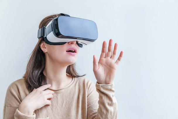 Mosolyogj fiatal nő visel virtuális valóság VR szemüveg sisak fejhallgató fehér háttérrel. Okostelefon használata virtuális valóság szemüveg. Technológia, szimuláció, hi-tech, videojáték koncepció. - Fotó, kép
