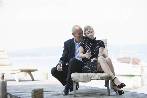 happy senior couple sitting on bench at pier - Photo, Image