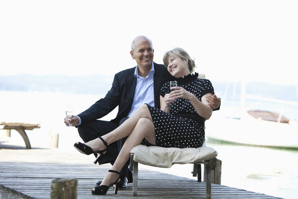 ηλικιωμένο ζευγάρι κάθεται στον πάγκο και μιλάει στο τηλέφωνο - Φωτογραφία, εικόνα