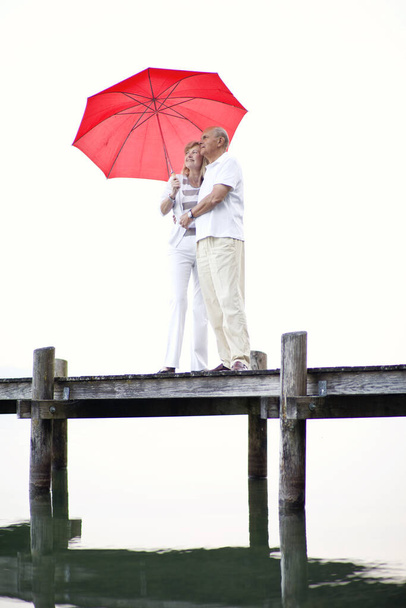 couple in love with umbrella and a red heart - Фото, изображение