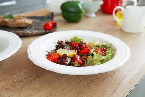 Plate with tasty prepared salad on table in kitchen - Valokuva, kuva