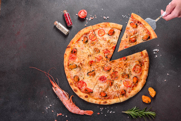 Вкусная нарезанная пицца с морепродуктами и помидорами на бетонном фоне
 - Фото, изображение