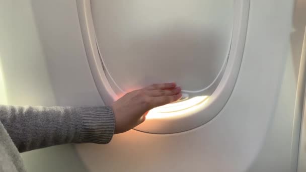 woman hand is opening  window of airplane. Clouds and sky as seen through window of an aircraft, air plane. - Video