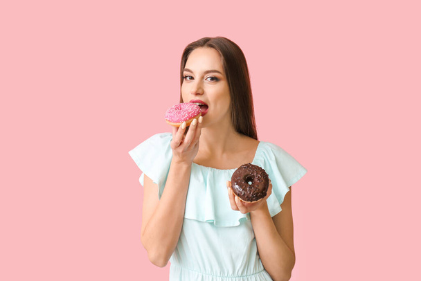 Beautiful young woman with donuts on color background - Photo, image