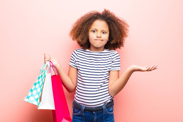 african american little girl  against flat wall with shopping bags - Photo, image