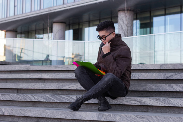 young male Asian student sitting on steps of University read books and thought - Фото, зображення