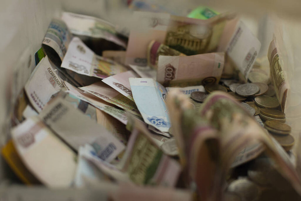 Orosz pénz valuta rubel, fém érmék és papír jegyzetek egy dobozban gyűjtésére jótékonysági adományok. Jótékonysági gyűjtés, rubel és egy penny.. - Fotó, kép