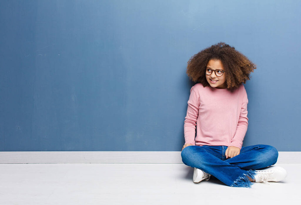 african american little girl looking worried, stressed, anxious and scared, panicking and clenching teeth sitting on the floor - Fotoğraf, Görsel