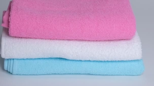 weiße, rosa und blaue saubere Handtücher und ein Baumwollzweig auf weißem Hintergrund. Zeitlupe in Nahaufnahme - Filmmaterial, Video