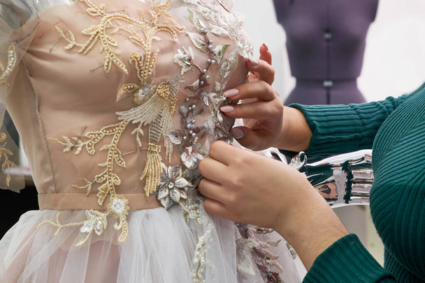 Dressmaker fixing white lace wedding dress on a mannequin in tailor studio - Photo, image