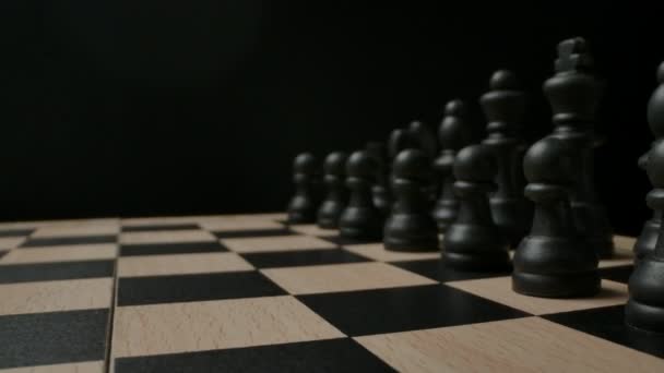Black chess pieces on black and white checkerboard. Wide macro dolly in. - Footage, Video