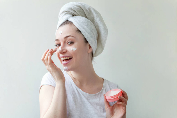Schönheitsporträt einer Frau in Handtuch auf dem Kopf mit weißer Pflegemaske oder Creme im Gesicht, weißer Hintergrund isoliert. Reinigung der Haut Öko-Kosmetik Wellness-Entspannungskonzept. - Foto, Bild