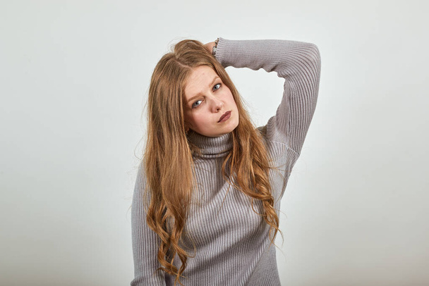 red haired woman in gray sweater stylish cool look straightens hair with hand - 写真・画像