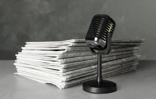 Newspapers and vintage microphone on light grey stone table. Jou - Fotografie, Obrázek