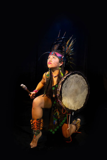 young woman Teotihuacana, Xicalanca - Toltec in black background, with traditional dress dance with a trappings with feathers and drum - Foto, Imagen