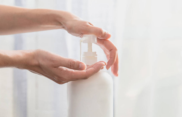 Woman hands pushing pump plastic soap bottle on white background - Photo, Image