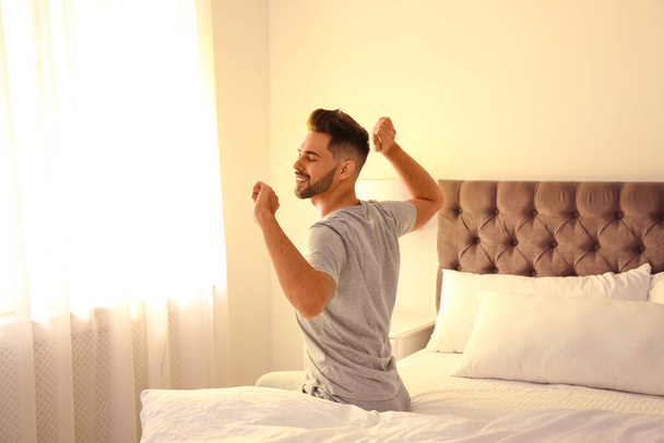 Young man stretching on bed at home. Lazy morning - Foto, imagen