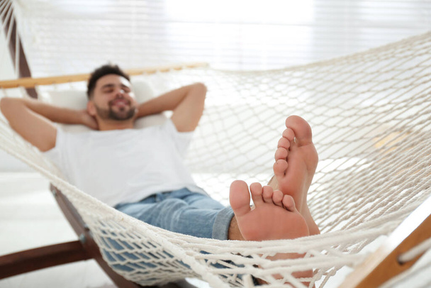 Young man relaxing in hammock at home, focus on feet - Fotoğraf, Görsel