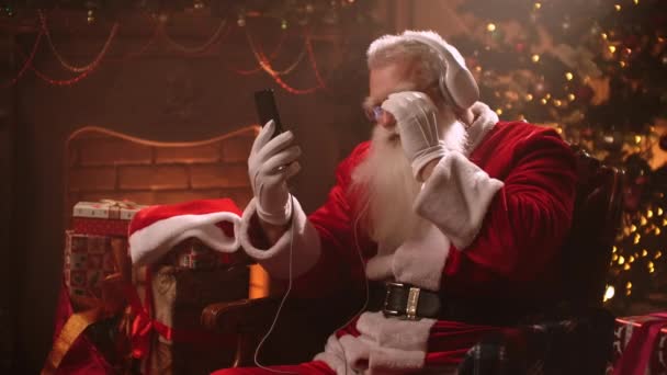 Vanhempi mies, jolla on valkoinen parta, kuuntelee musiikkia kuulokkeilla ja joulupukin puvulla jouluaattona. Joulupukki uutena vuotena. Jolly vanhempi mies tanssii musiikkia
 - Materiaali, video