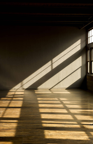 Image of a vacant loft with late evening light streaming thru windows onto hardwood floors. - Photo, image