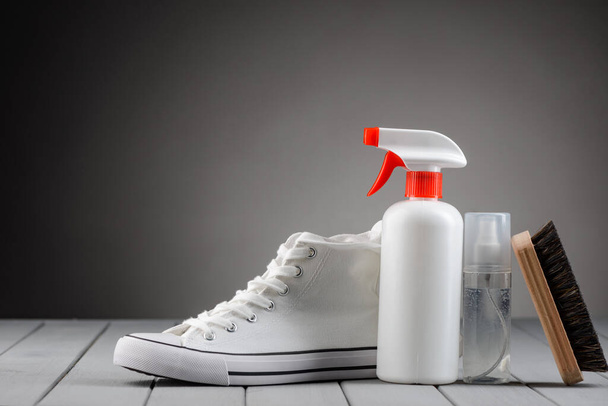 White sneaker, cleaner spray and brush on gray background - Fotografie, Obrázek