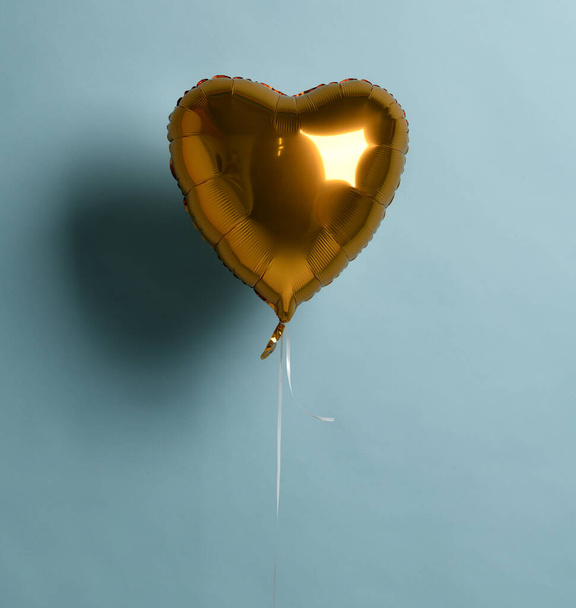 Metallic foil single gold heart balloon object for birthday party or valentines day on pastel color light blue - Foto, Bild