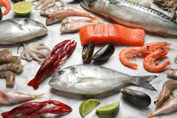 Φρέσκα ψάρια και διάφορα θαλασσινά σε λευκό μαρμάρινο τραπέζι - Φωτογραφία, εικόνα