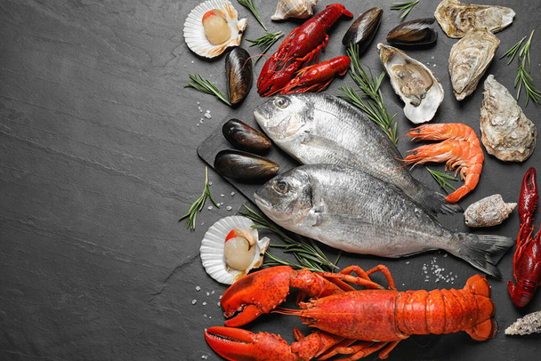 Fresh fish and different seafood on black table, flat lay. Space for text - Fotoğraf, Görsel