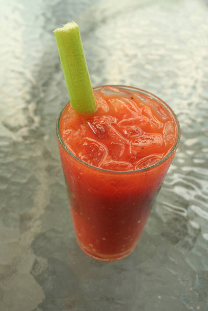 a Bloody Mary Coctail with celery on a glass table - Foto, immagini