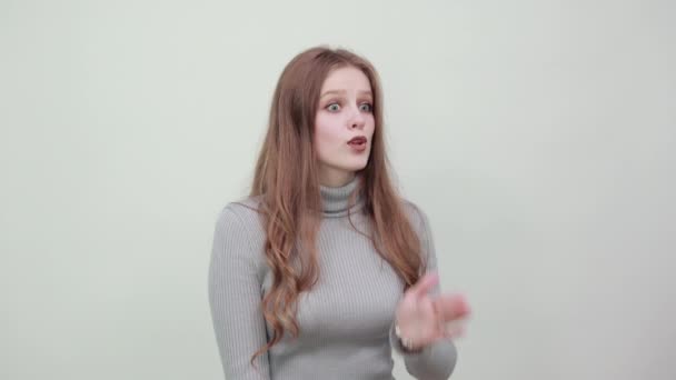 グレーのセーターの女性は頬に手を触れるとショックを受け口を開く - 映像、動画