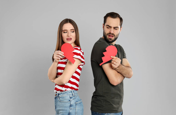 Couple with torn paper heart on grey background. Relationship problems - Photo, image