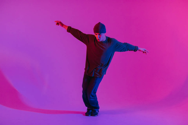 Fiatal férfi ugró tánc kortárs tánc a stúdióban. Reggeli tánc. Tánciskola plakát. Fénymásolási tér. Harci versenykiírás. Rózsaszín és kék háttér. - Fotó, kép