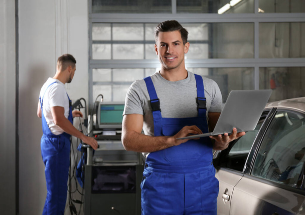 Mechanic with laptop doing car diagnostic at automobile repair s - Foto, Imagem