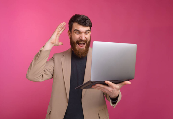 Φωτογραφία του έκπληκτου επιχειρηματία που δείχνει σοκαρισμένος στο laptop - Φωτογραφία, εικόνα