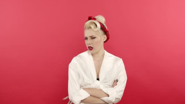 Offended pin up girl posing with crossed arms on pink background - Footage, Video