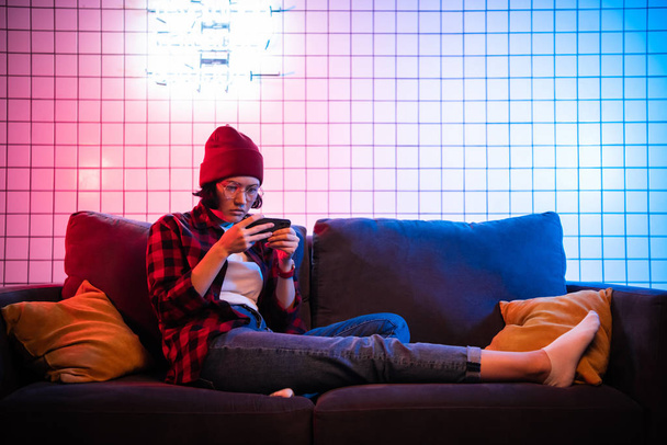 Gros plan portrait d'une jolie adolescente jouant à un jeu en ligne au téléphone portant un jean décontracté vêtements de chemise en denim assis sur un canapé confortable
 - Photo, image