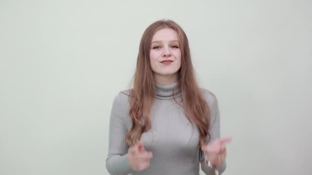 vrouw in grijs trui is gelukkig maakt gaten in wangen met index vingers, glimlachen - Video