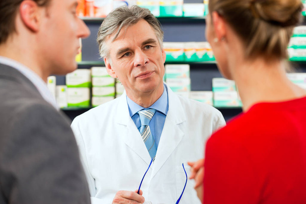 pharmacist in his pharmacy with customers - Foto, Imagem